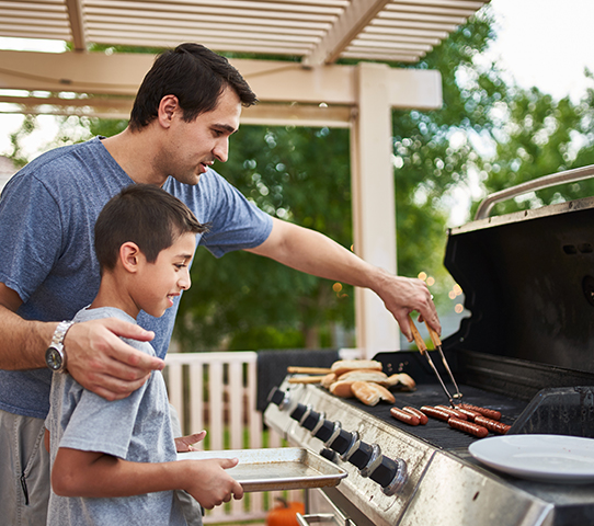 father and son grill using propane tank refilled grill
